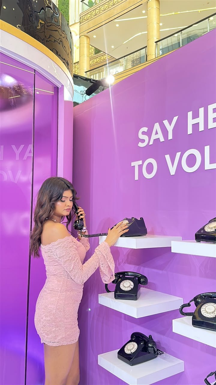 Vaishnavi Kadekar in a pink lace dress holding a vintage telephone at a brand installation